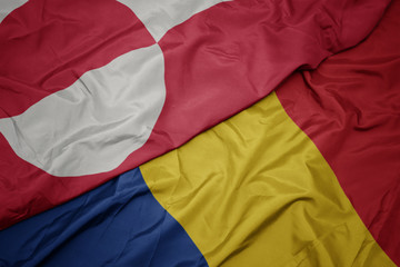waving colorful flag of romania and national flag of greenland.