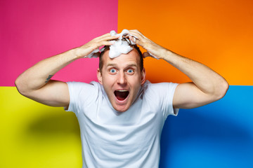 Portrait of a young, handsome, cheerful guy on a multi-colored background, dressed in a white...