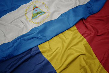 waving colorful flag of romania and national flag of nicaragua.