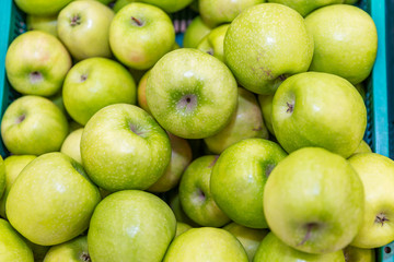 Green apples on the counter in the supermarket. Close-up. Background. Space for text. Healthy eating and vegetarianism.