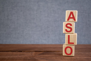 Abbreviation ASLO (anti-streptolysin O) text acronym on wooden cubes on dark wooden backround. Medicine concept.