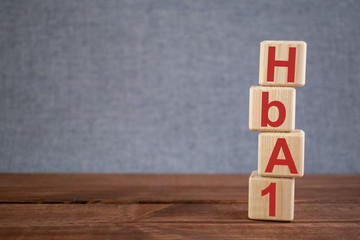 Abbreviation HbA1 (glycosylated hemoglobin) text acronym on wooden cubes on dark wooden backround. Medicine concept.