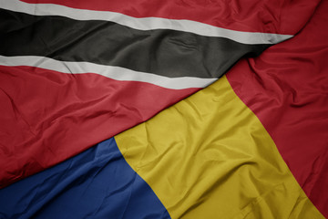 waving colorful flag of romania and national flag of trinidad and tobago.