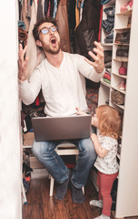 Busy father trying to find a quiet place in a wardrobe  to hide from children for a work at the...