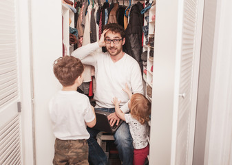 Busy father trying to find a quiet place in a wardrobe  to hide from children for a work at the...