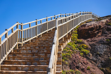 Fototapeta premium Escalera exterior de piedra con valla de madera en la costa junto al mar
