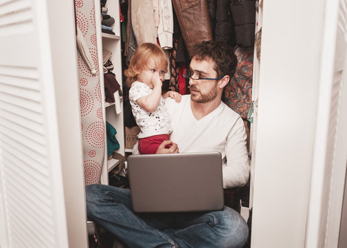 Busy Father Trying To Find A Quiet Place In A Wardrobe Between Clothes  To Hide From Children For A Work At The Laptop. Work From Home. Home Office. Quarantine. Freelancer.