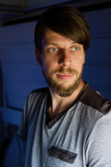Obraz premium Handsome young caucasian man with a beard portrait, looks outside of the train's window, looking bored or tired of traveling too long.
