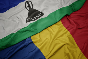 waving colorful flag of romania and national flag of lesotho.