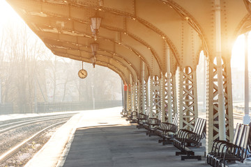 Empty platform with clock at railway station, sunny day.