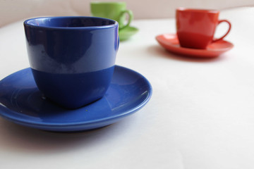 blue or red Cup mug with saucer on a white background there are green and red mugs at the back with a place to insert text