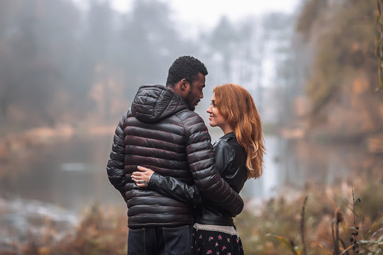 Interracial couple posing in autumn leaves background