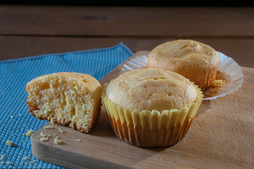 Cornmeal cupcakes on an old cutting board, cupcake crumbles on a blue tablecloth
