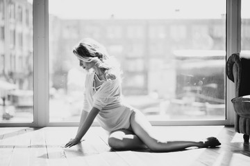 Beautiful  pregnant woman in a white transparent blouse on the background of a window in the backlight. Black and white photo. Fine art. Expectation of a child. Soft selective focus.