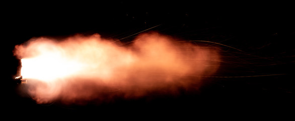 A shot from a firearm on a black background, a fiery exhaust with flying sparks, flames bursting out of the pipe - 336506518