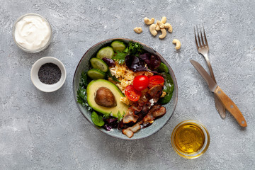 Ketogenic food: avocado, tomatoes, fresh salad, eggs, nuts, bacon, olive oil on grey background, top view