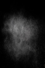 White dust is scattered by an explosion on a black background, an abstract cluster of white particles, a snowstorm on a black background