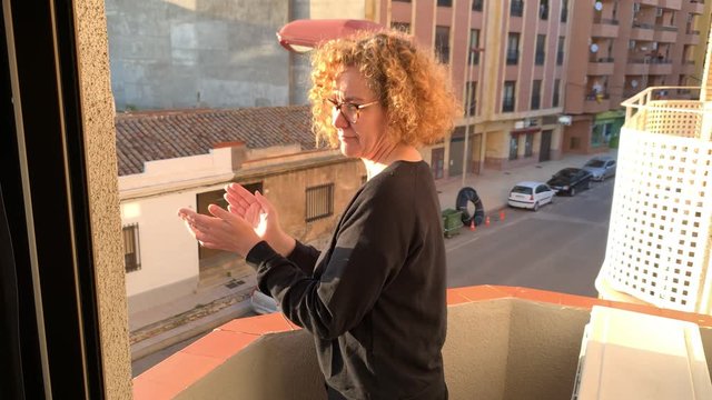 Blonde Spanish woman applauds all the health personnel from the balcony of her apartment during the quarantine of COVID 19 in Spain.