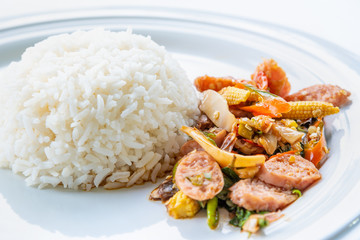 Asian spicy hot food or Thai food, closeup side view Thai sour pork or Nham fried with pepper and mixed vegetable with white cooked rice on round white plate background for cooking delicious meals