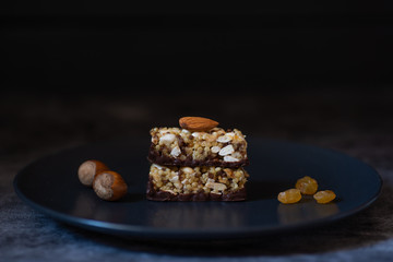 Dark plate with healthy whole grain candies on a dark background decorated with almonds