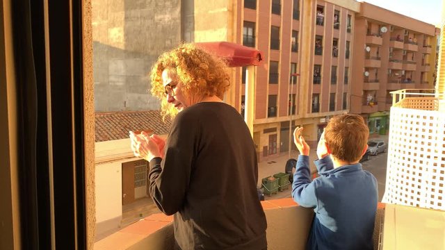 A Spanish woman and her son applaud from the balcony of their apartment for the COVID 19 pandemic health team.