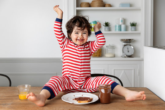 Happy toddler with chocolate smeared face sitting on kitchen table