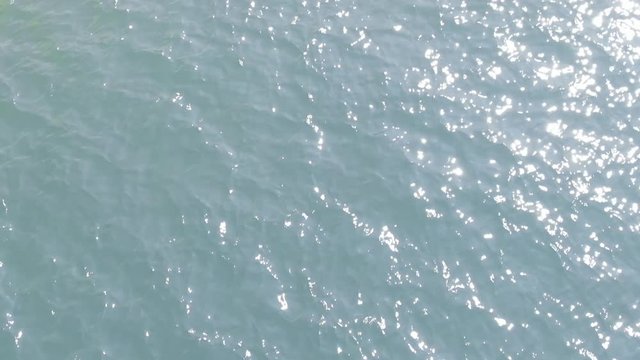 slow motion of light blue wave moving in the sea with sun reflection. Ripple surface of water.