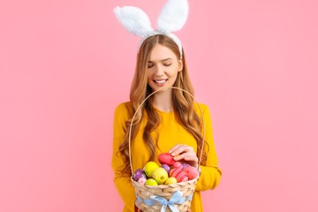 Obraz na płótnie Canvas Happy Easter. happy young woman wears rabbit ears on Easter day and holds a basket of Easter eggs, on an isolated pink background