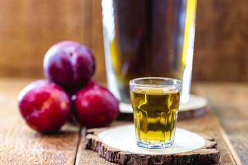 alcoholic drink made from plum, fruit liqueur with rustic wooden background.