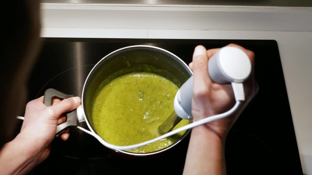 Close up of man crushing vegetables with a mixer.