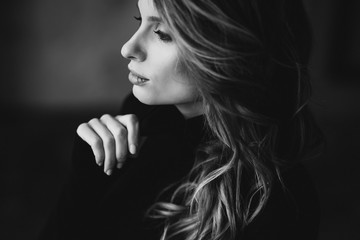 Beautiful woman with curls and full lips in a black turtleneck. Black and white art photo. Soft selective focus.
