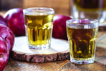 glass of plum liqueur, drink made from fruit-based alcohol. Rustic wood background.