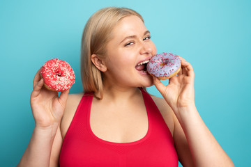 Fat girl eats sweet instead of do gym. Cyan background
