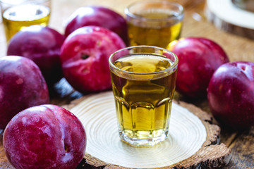 glass of plum liqueur, drink made from fruit-based alcohol. Rustic wood background.
