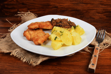 breaded chicken breast with boiled potatoes and fried cabbage
