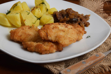 breaded chicken breast with boiled potatoes and fried cabbage