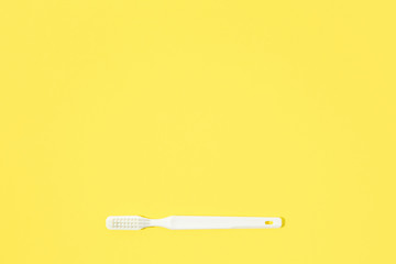Toothbrush on yellow pastel background.