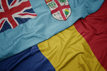 waving colorful flag of romania and national flag of Fiji .