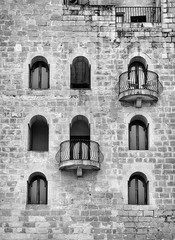Black and white image of ancient brick building with 
windows and balconies.