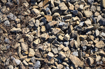 Gray gravel stones with dry grass in a road construction. Bank of the river. crushed stone texture