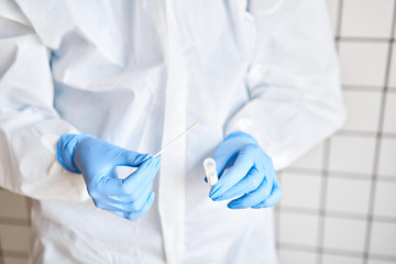 Doctor holding swab test tube for 2019-nCoV analyzing. Coronavirus test. Blue medical gloves and protective face mask for protection against covid-19 virus. Coronavirus and pandemic.
