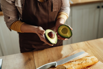 Close-up of woman using avocado while preparing food in the kitchen.