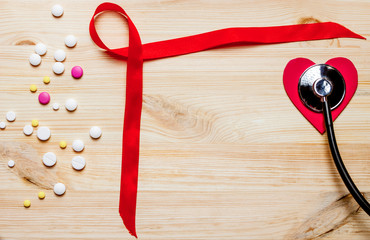 Red ribbon,pills,stethoscope, decorative red heart on a wooden table. 1 December World AIDS Day, HIV illness campaign. Copy space for text. Top view/