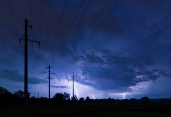 Silhouette of power lines on thunderstorm with lightnings background