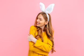 Holiday season of rabbit and eggs. Happy woman in Easter Bunny ears isolated on pink background.