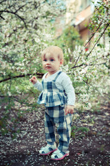 little one-year-old girl walking in   spring garden.