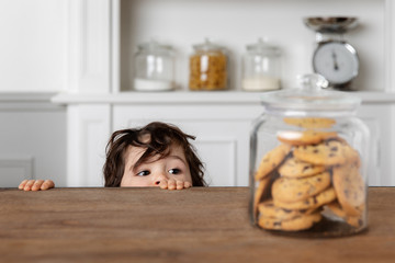 Toddler looking at cookie jar on kitchen table