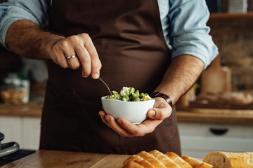 Close-up of man using avocado while preparing healthy meal in the kitchen.