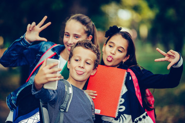 Portrait of happy little school kids taking selfie in the park.