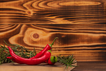 Red chili peppers and rosemary twigs on a cutting board. Fresh vegetables, healthy organic food concept